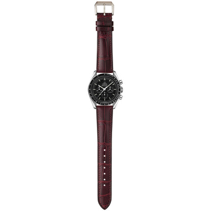 Burgundy crocodile leather watch strap fitted to a black-dial chronograph, shown in a full-length flat lay.