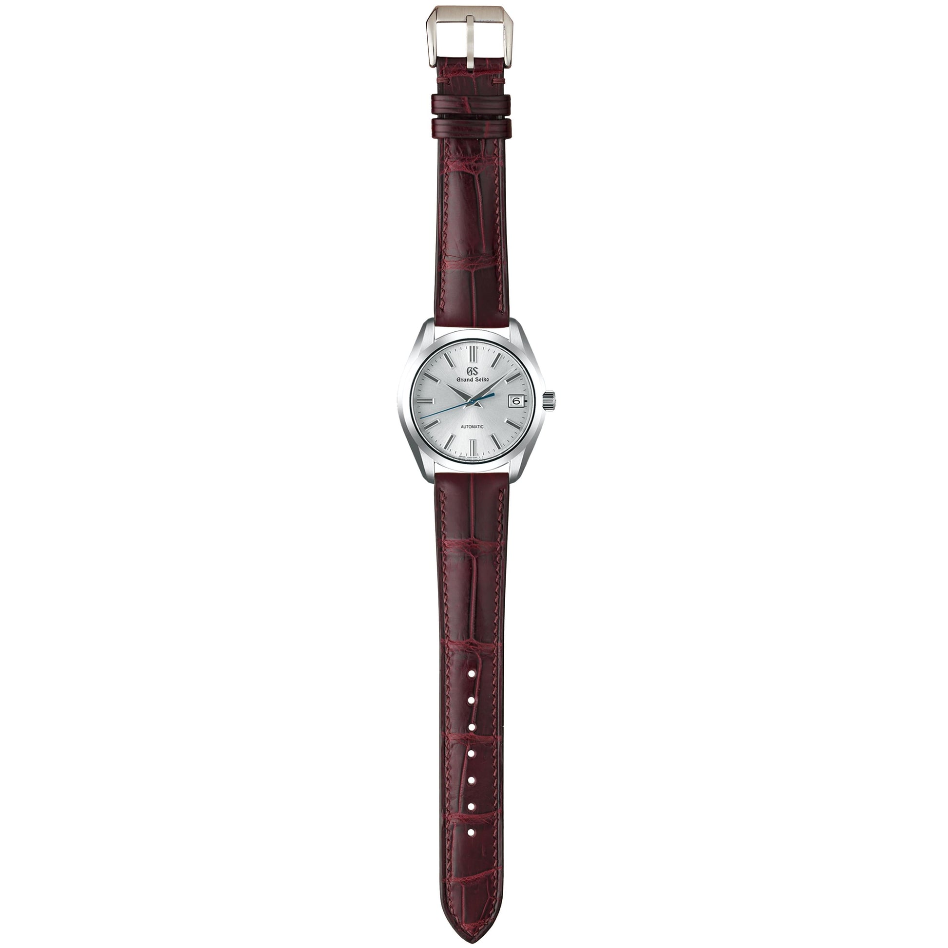 Burgundy crocodile leather watch strap fitted to a white-dial dress watch, shown in a full-length flat lay.