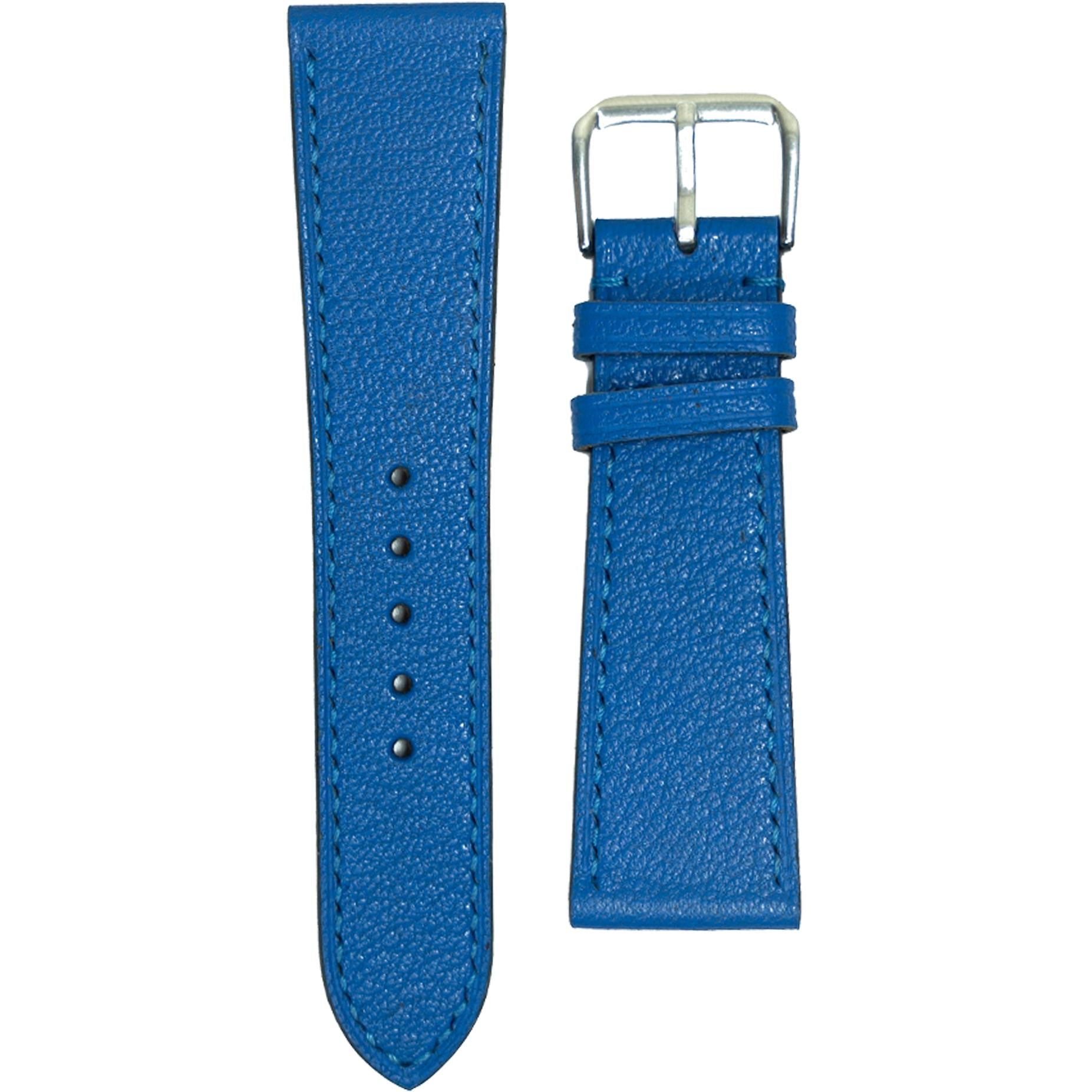 Blue Alran goat leather watch strap with matching stitching and silver buckle, flat lay.