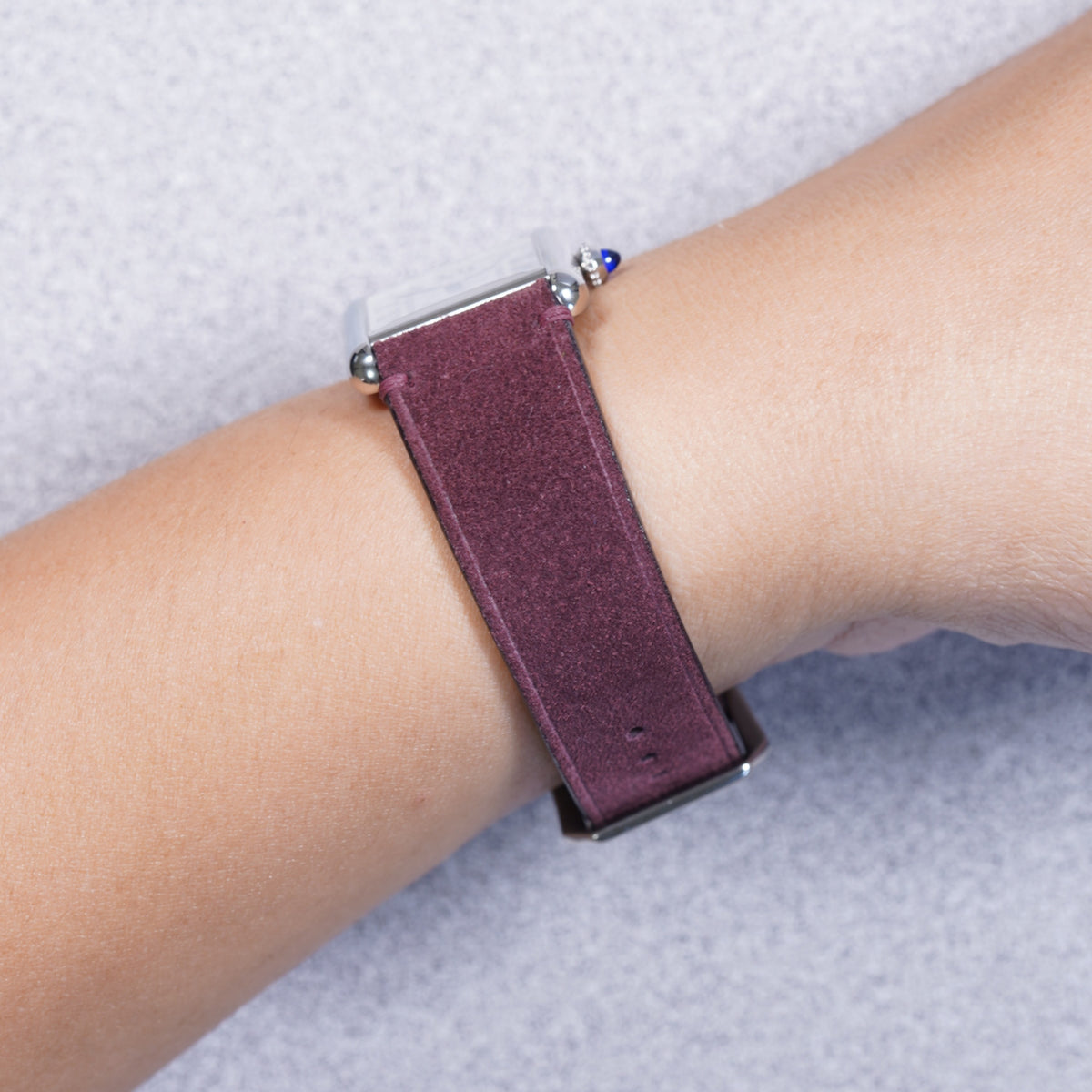 Cartier Tank Must with a maroon suede leather strap, strap detail on the wrist