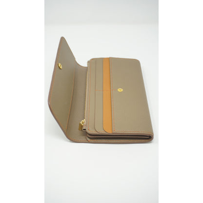 Epsom leather clutch wallet in taupe with orange stitching and accent, open with gold hardware.