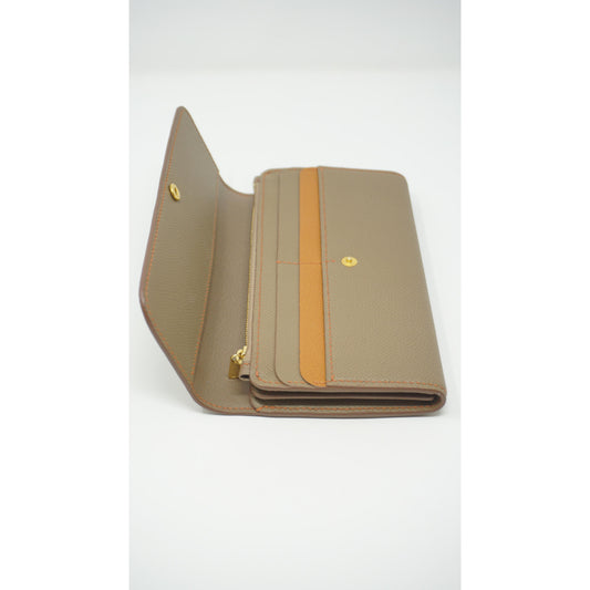 Epsom leather clutch wallet in taupe with orange stitching and accent, open with gold hardware.