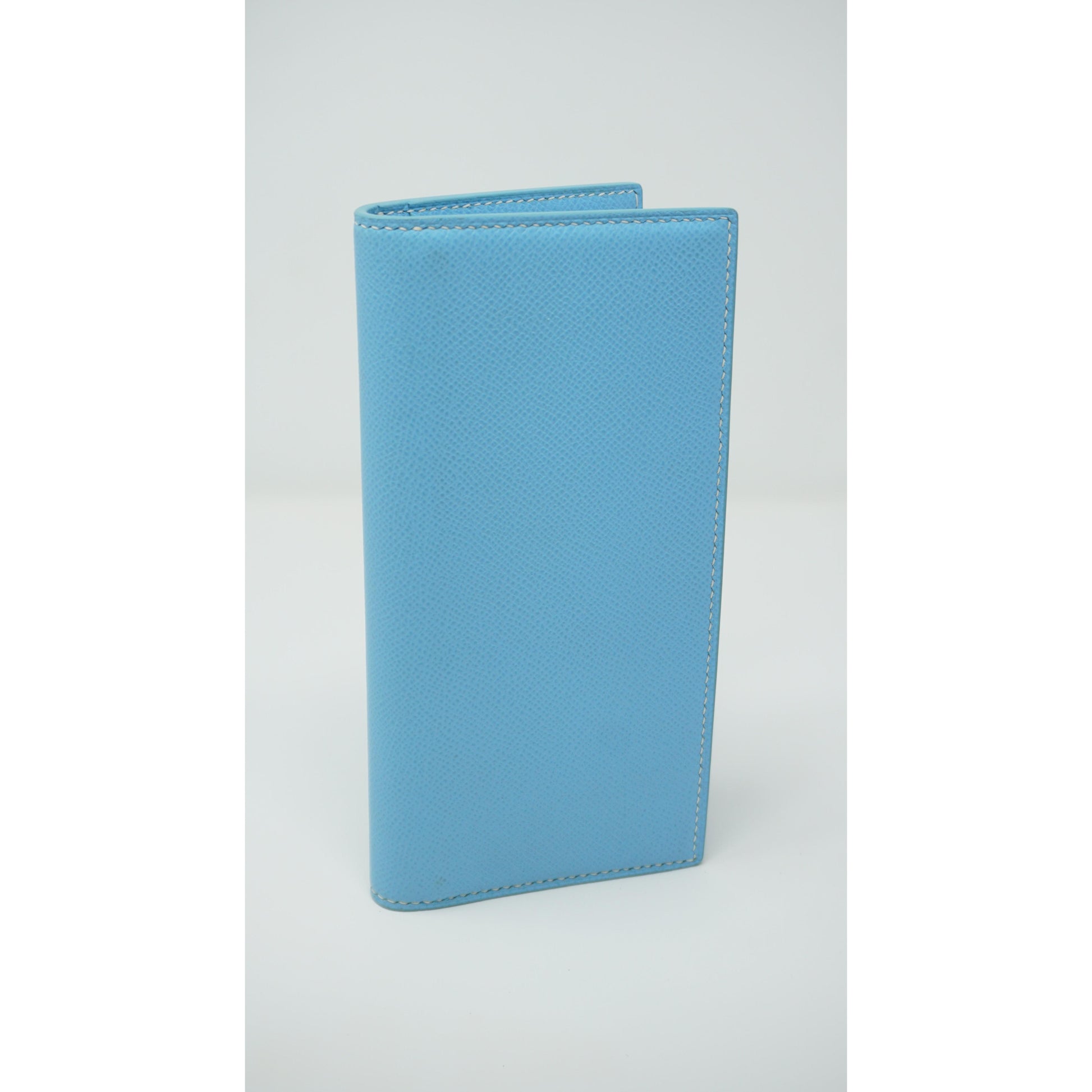 Light blue Epsom leather clutch with white stitching, standing upright.