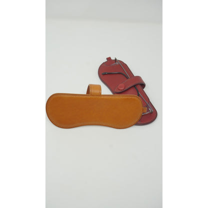 Tan Vachetta leather sunglasses holder with a red leather watch strap, flat lay.