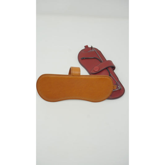 Tan Vachetta leather sunglasses holder with a red leather watch strap, flat lay.