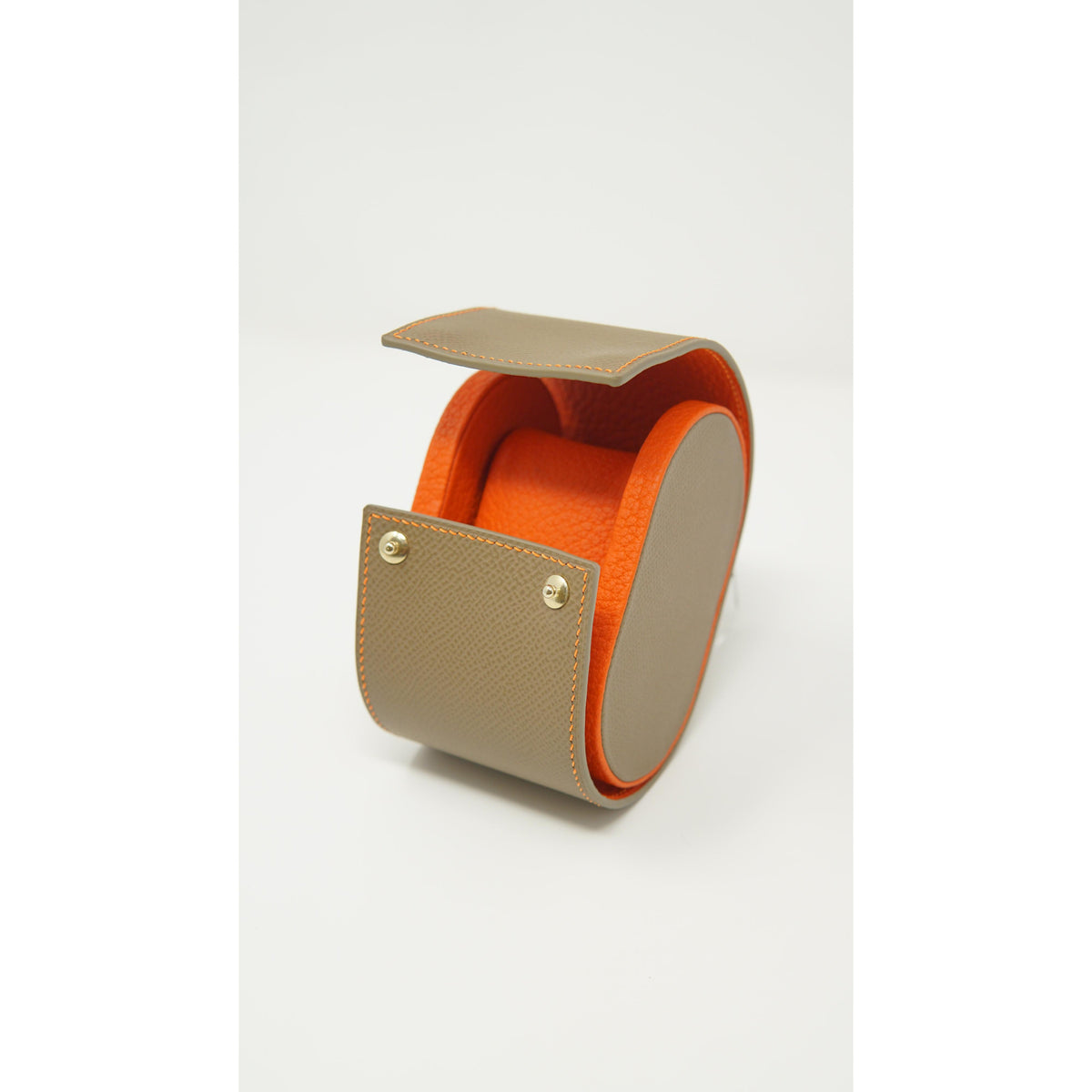 Single watch roll in taupe leather with orange interior and stitching, featuring a leather watch strap.