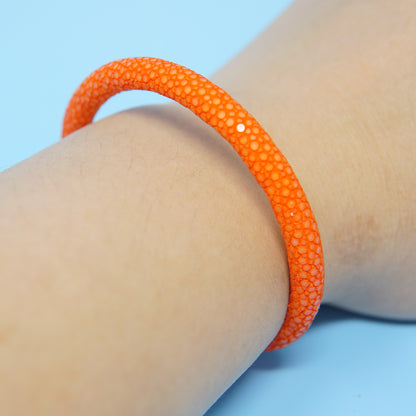 Orange stingray leather bracelet on a wrist, showcasing its textured surface and a single white accent.