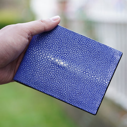 Hand holding a blue stingray leather wallet with a prominent white "eye" pattern.
