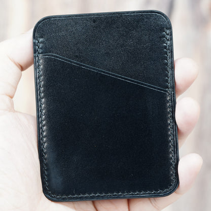 Hand holding a black minimalist leather card holder with visible stitching and a front card slot.