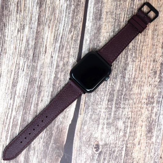 Burgundy Epsom leather watch strap for Apple Watch with black buckle, flat lay.