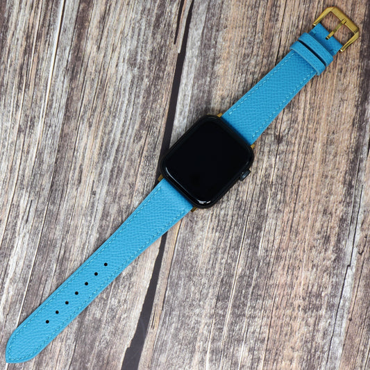 Tiffany Blue Epsom leather watch strap for Apple Watch with gold buckle, flat lay.