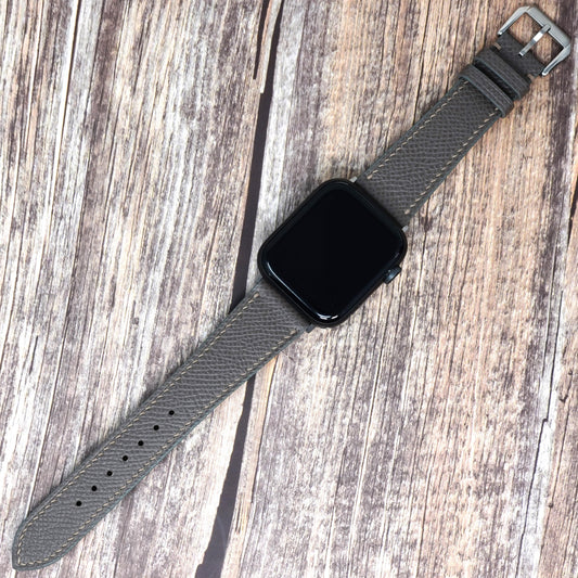 Gray Epsom leather watch strap with gray stitching and a black Apple Watch, flat lay.