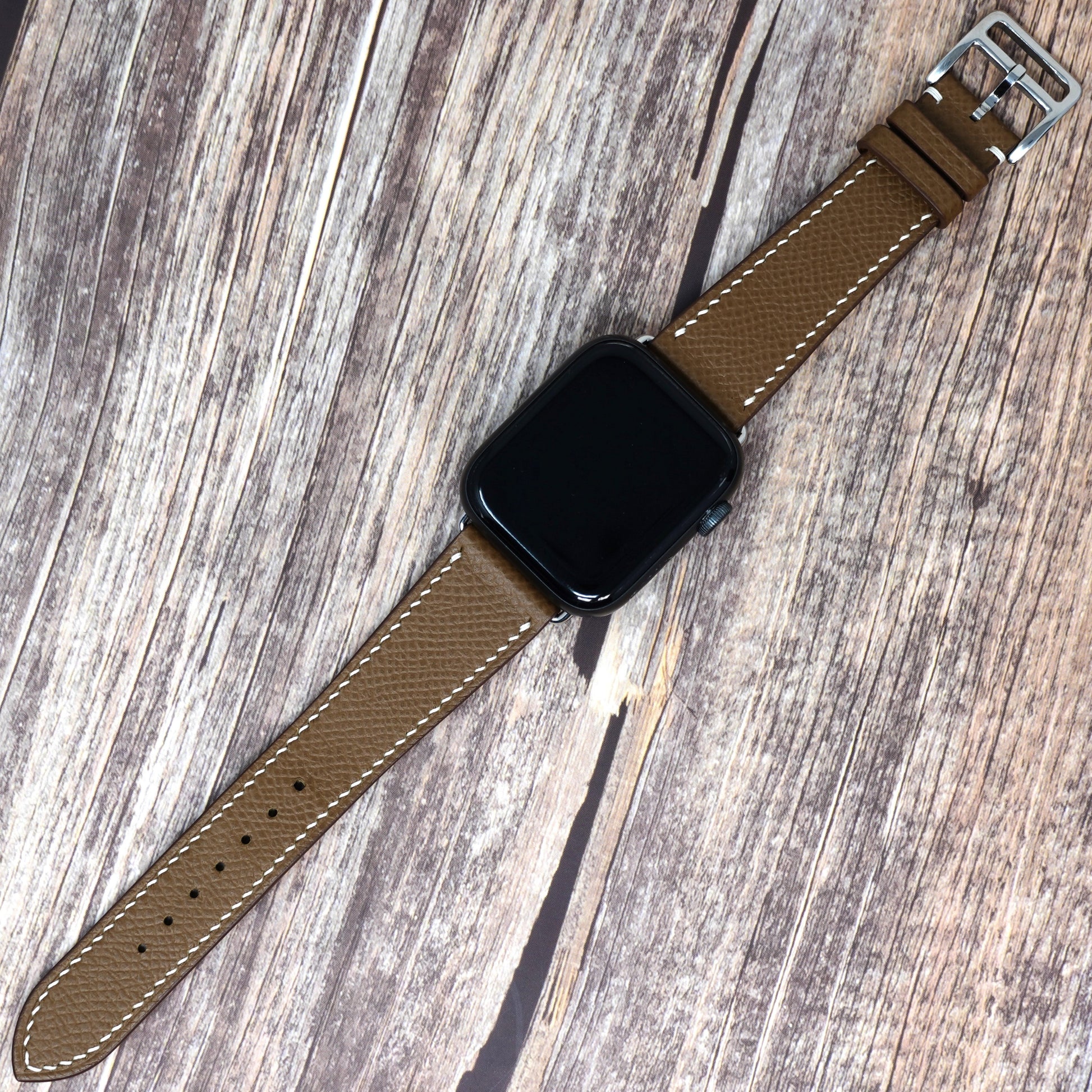 Brown Epsom leather watch strap with white stitching and silver buckle, flat lay.