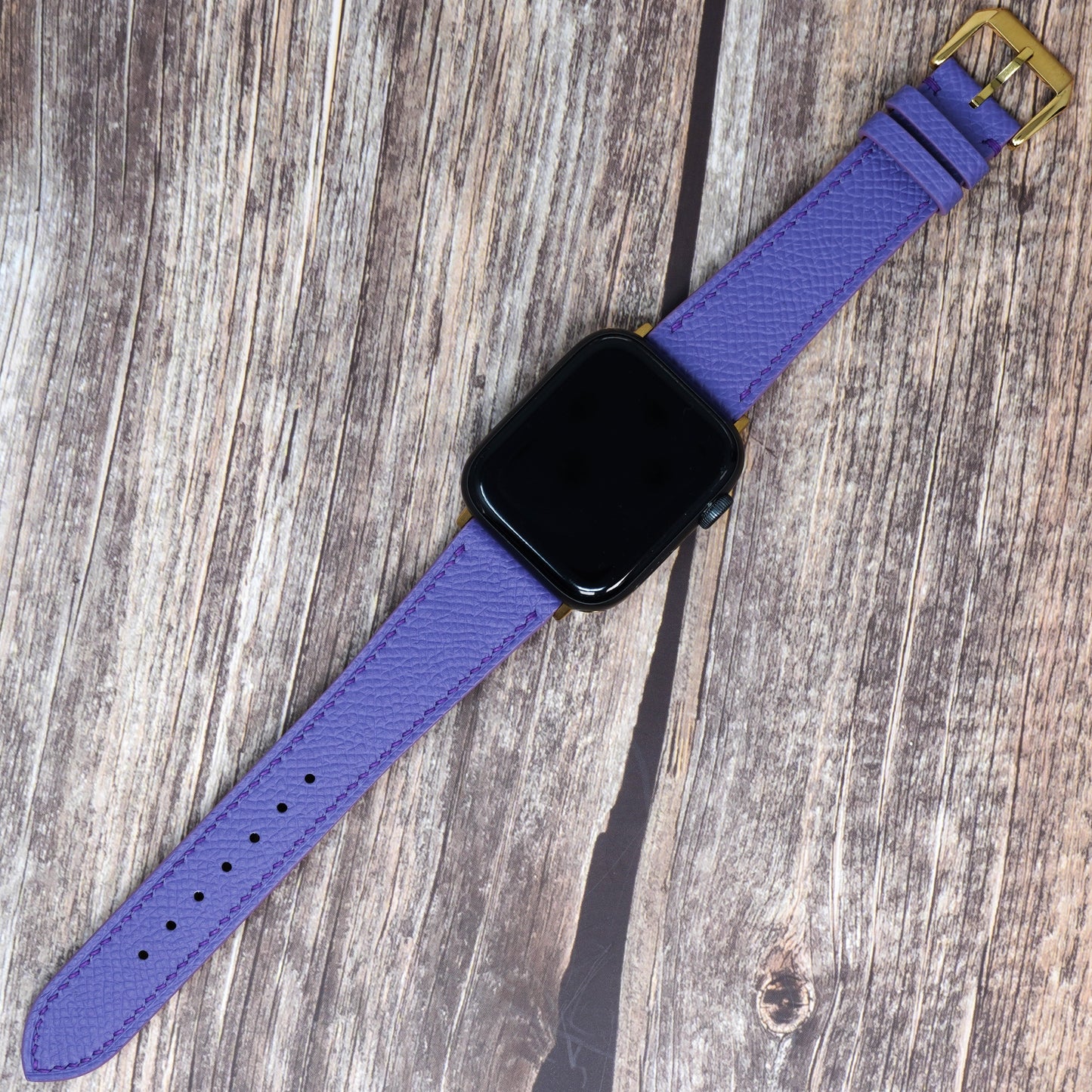 Purple Epsom leather watch strap with gold buckle, flat lay.