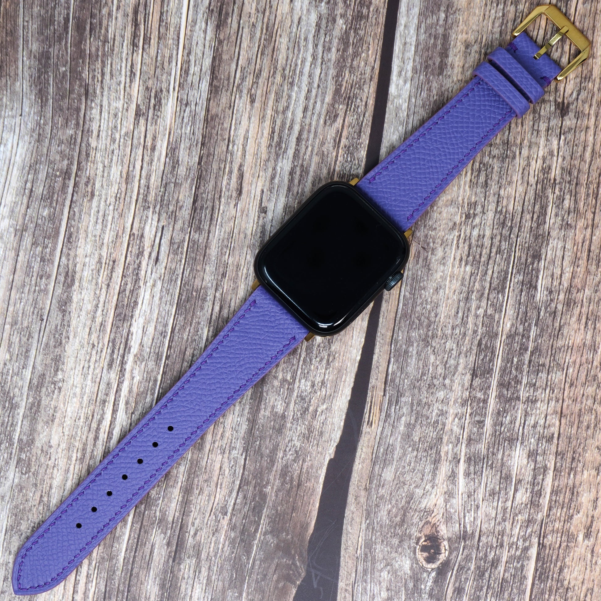 Purple Epsom leather watch strap with gold buckle, flat lay.