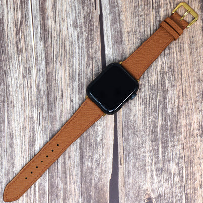 Tan Epsom leather watch strap for Apple Watch, flat lay on wood.