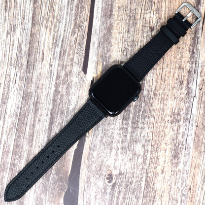 Black Epsom leather watch strap for Apple Watch with silver buckle, flat lay.