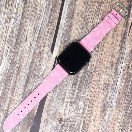 Pink Epsom leather watch strap for Apple Watch, flat lay on wood.