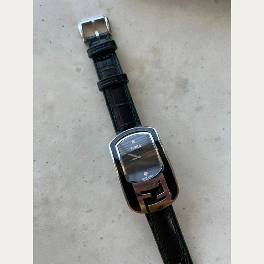 Dark green crocodile leather watch strap fitted to a rectangular Fendi watch, showing scales, stitching and green edges.