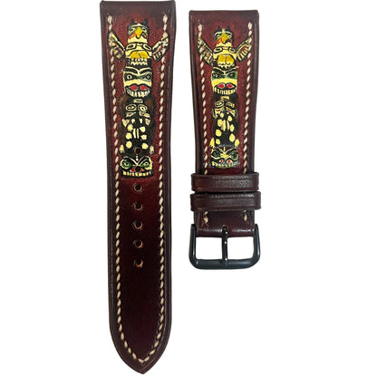 Engraved dark brown leather watch strap with colorful totem pole design and white stitching, flat lay.