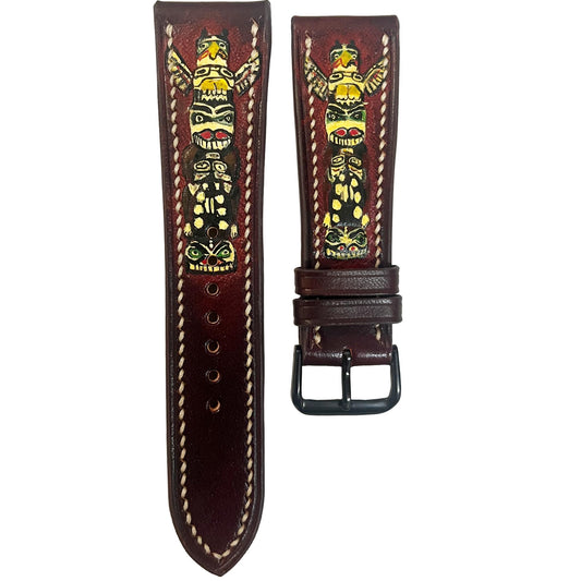 Engraved dark brown leather watch strap with colorful totem pole design and white stitching, flat lay.