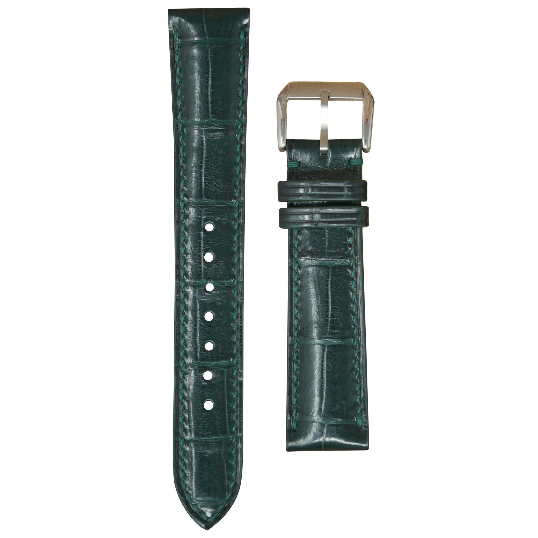 Dark green crocodile leather watch strap with matching stitching and a silver buckle, flat lay.