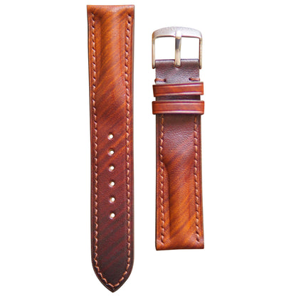 Brown patina leather watch strap with light stitching and silver buckle, flat lay.