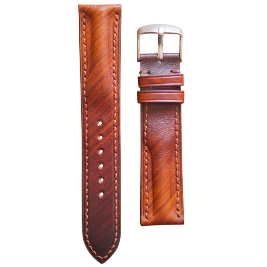 Brown patina leather watch strap with light stitching and silver buckle, flat lay.