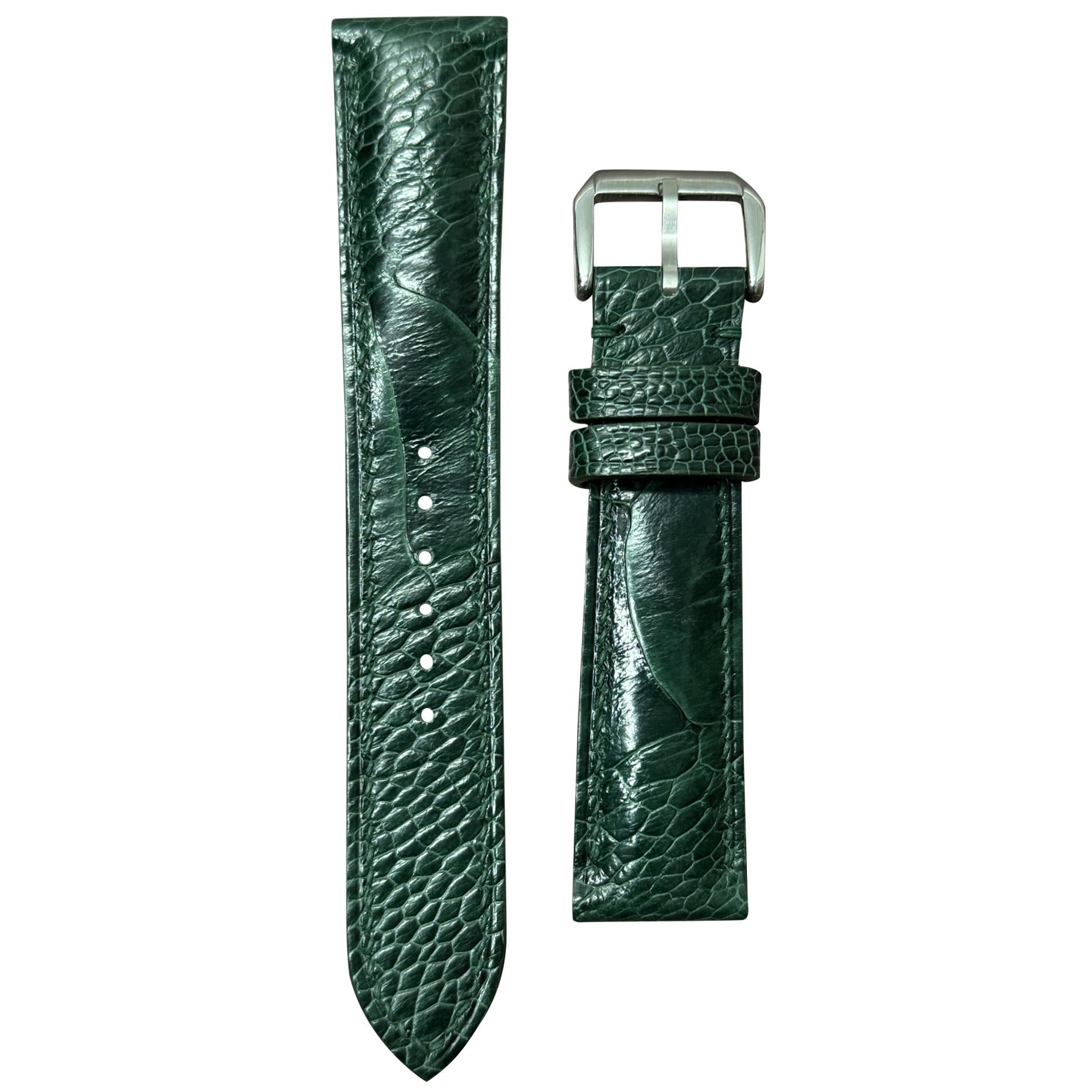 Green ostrich leg leather watch strap with silver buckle, flat lay.