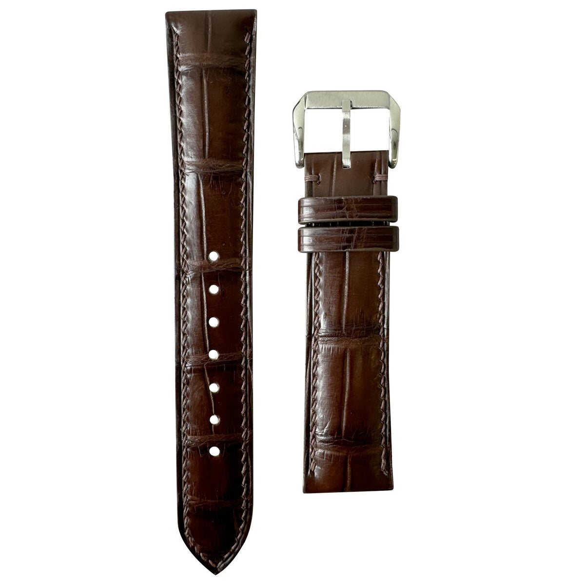 Brown crocodile leather watch strap with matching stitching and silver buckle, flat lay.