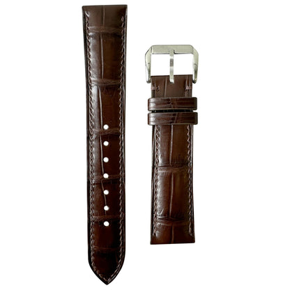 Brown crocodile leather watch strap with matching stitching and silver buckle, flat lay.