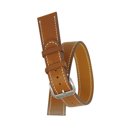 Brown leather double tour watch strap with white stitching and silver buckle, flat lay.