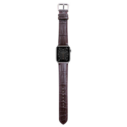 Brown crocodile leather watch strap with red stitching and silver buckle, flat lay.