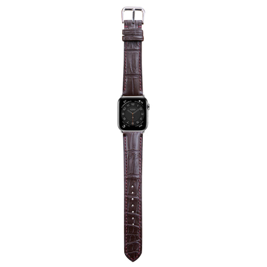 Brown crocodile leather watch strap with red stitching and silver buckle, flat lay.