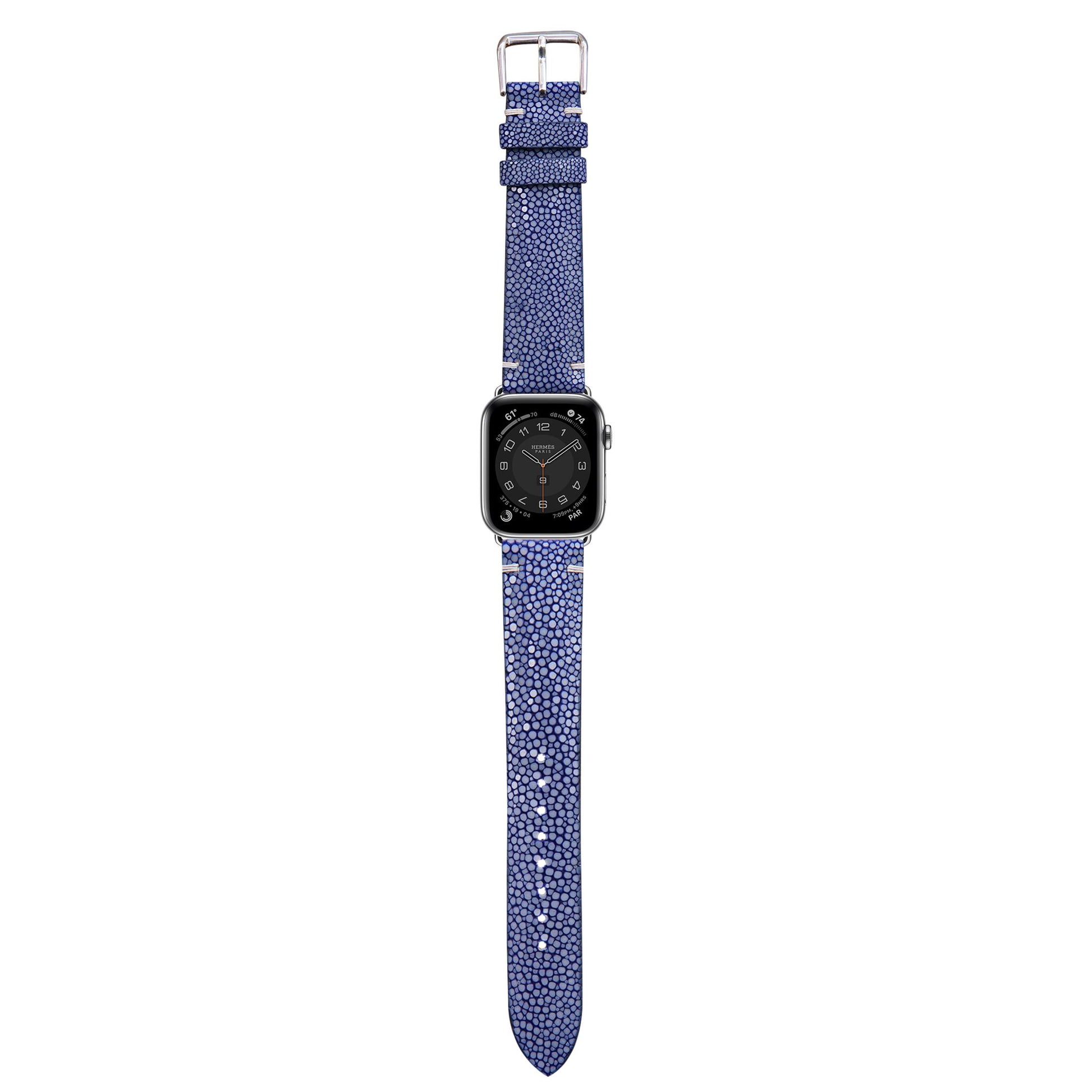 Blue stingray leather watch strap with silver buckle, attached to an Apple Watch, flat lay.