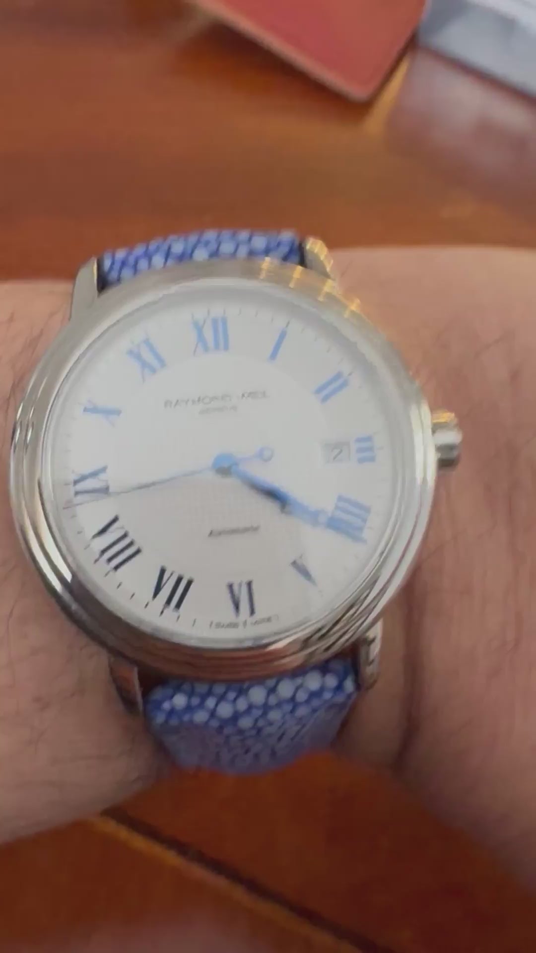 Customer wrist showing a blue stingray leather watch strap with close-up grain, keeper and buckle details.