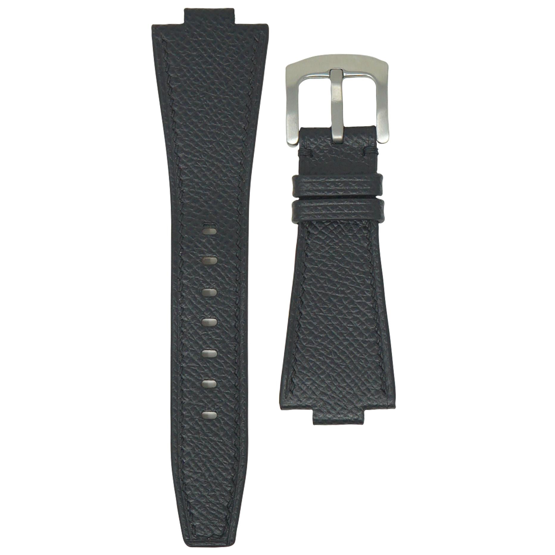 Black textured leather watch strap with silver buckle, flat lay.