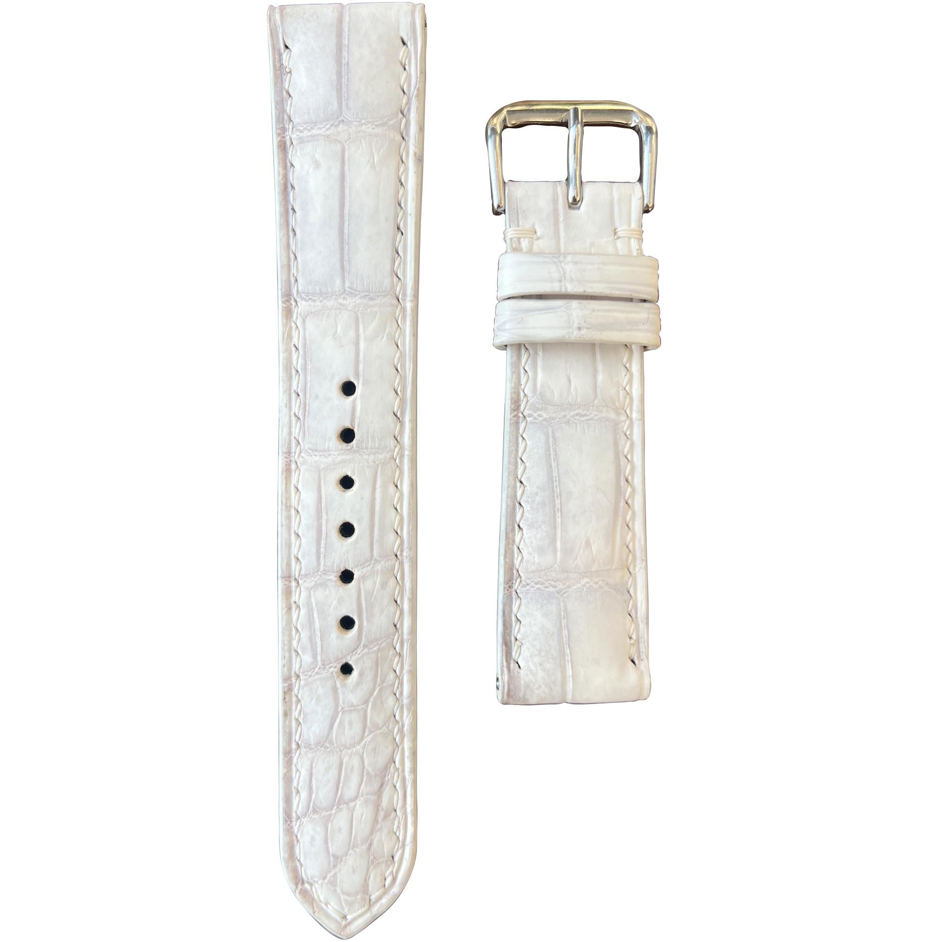 Sand white crocodile leather watch strap with white stitching and silver buckle, flat lay.