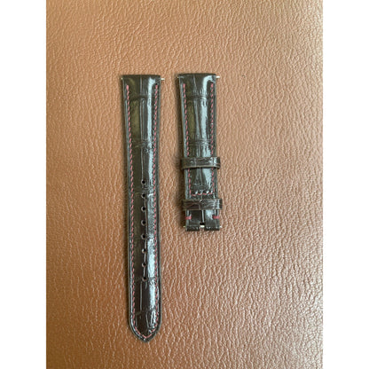Brown crocodile leather watch strap with red stitching, flat lay.