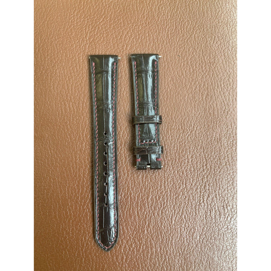 Brown crocodile leather watch strap with red stitching, flat lay.