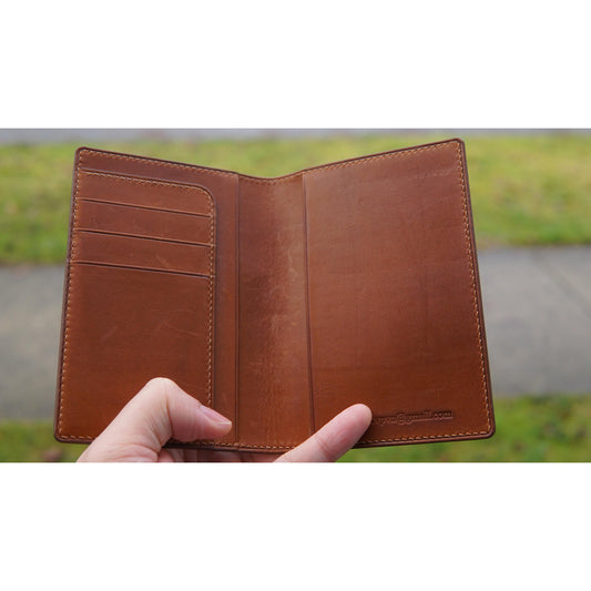 Brown Barenia leather passport holder, open view, with card slots on left and email engraved on right.